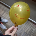 Balão amarelo com olhos e sorriso desenhados