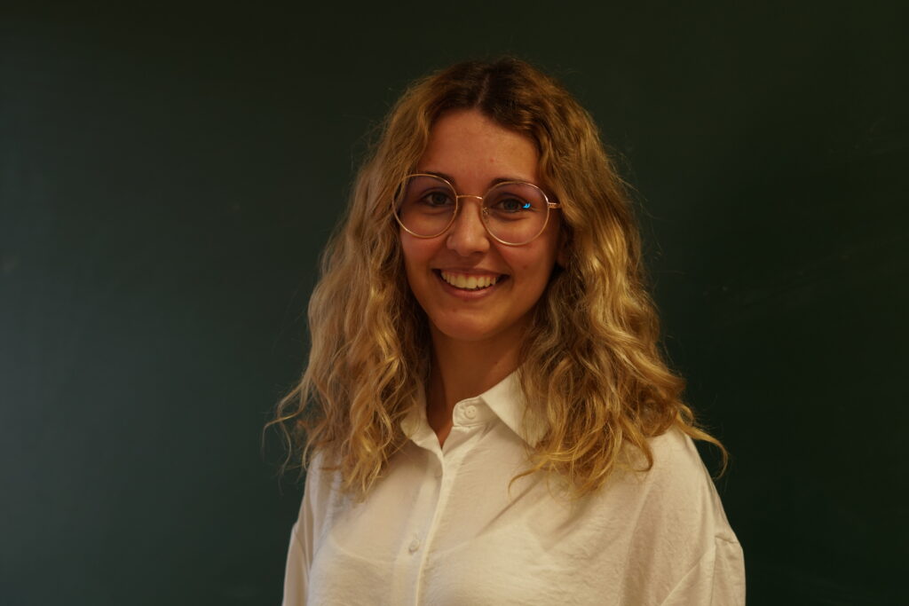 Bárbara Brochado a sorrir, com quadro de ardósia atrás. Representa a função de Content Manager na Teach For Portugal