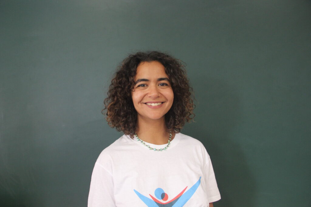 Teresa Fernandes, Mentora 5ª Geração Teach For Portugal a usar a camisola com o logótipo da Teach For Portugal com um quadro de ardósia como fundo