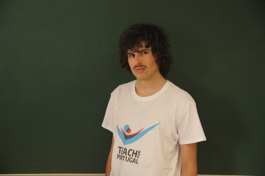 Renato Silva, Mentor 5ª Geração Teach For Portugal a usar a camisola com o logótipo da Teach For Portugal com um quadro de ardósia como fundo