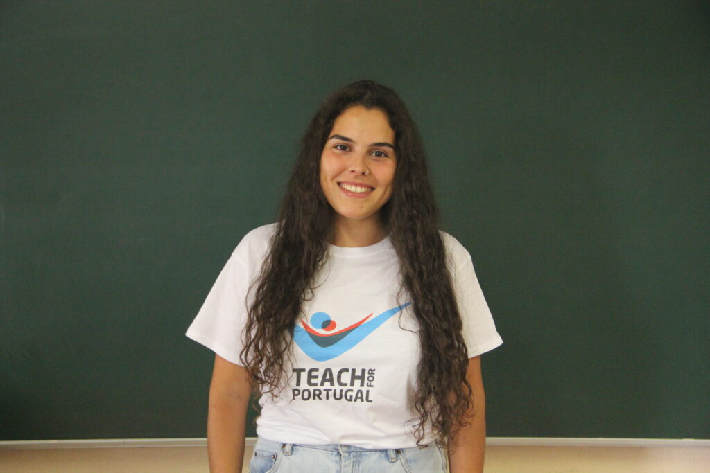 Catarina Martins, Mentora 5ª Geração Teach For Portugal a usar a camisola com o logótipo da Teach For Portugal com um quadro de ardósia como fundo
