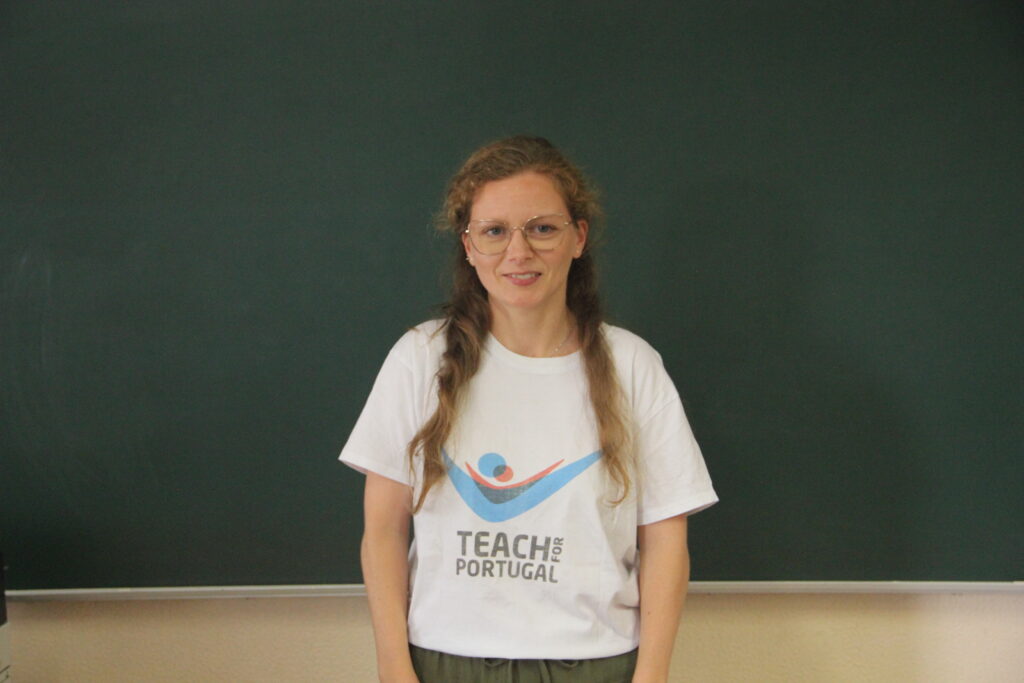 Adriana Salgado, Mentora 5ª Geração Teach For Portugal a usar a camisola com o logótipo da Teach For Portugal com um quadro de ardósia como fundo