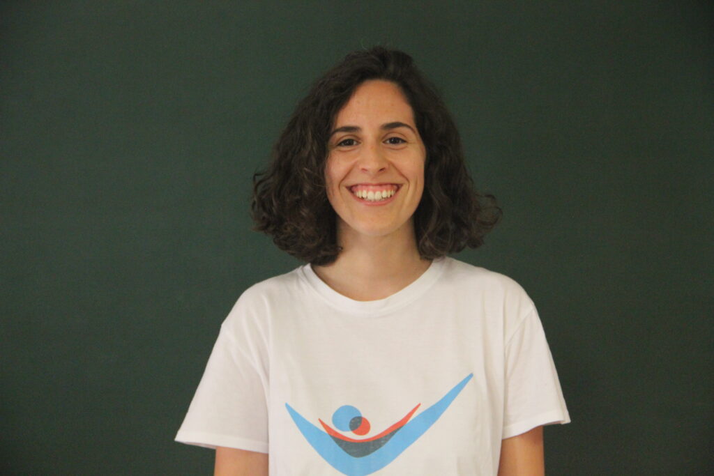 Madalena Vilar, Mentora 5ª Geração Teach For Portugal a usar a camisola com o logótipo da Teach For Portugal com um quadro de ardósia como fundo