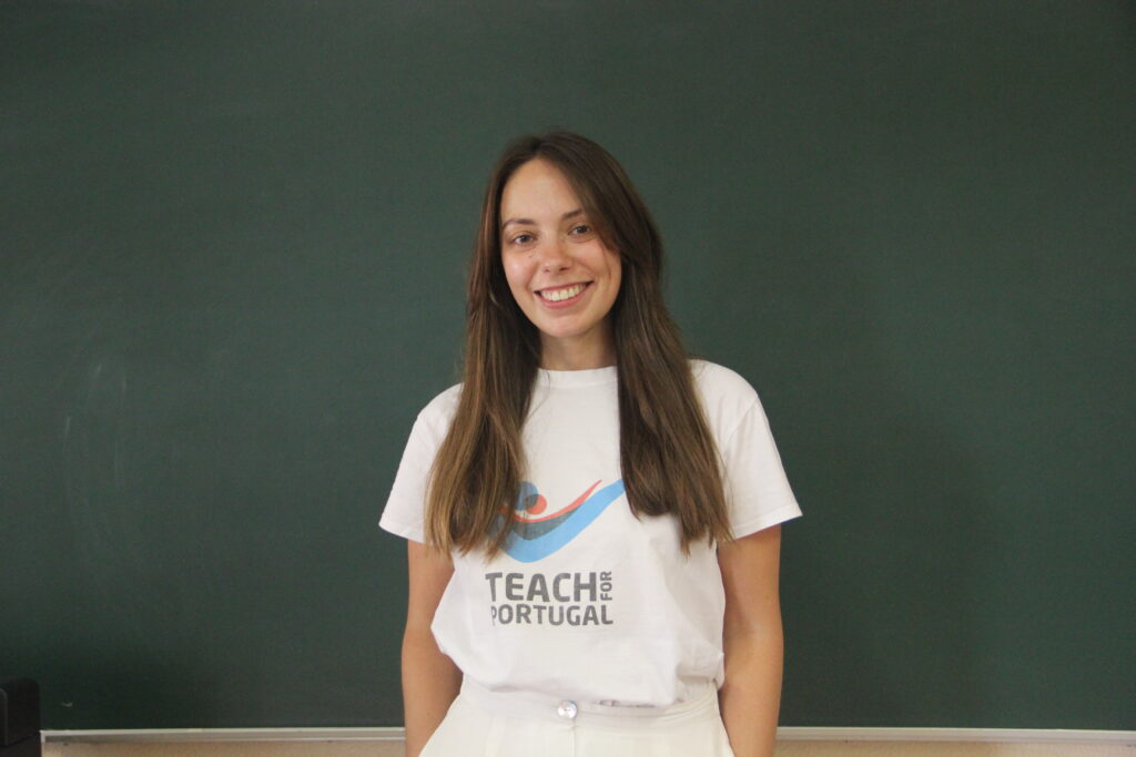 Margarida Vale, Mentora 5ª Geração Teach For Portugal a usar a camisola com o logótipo da Teach For Portugal com um quadro de ardósia como fundo