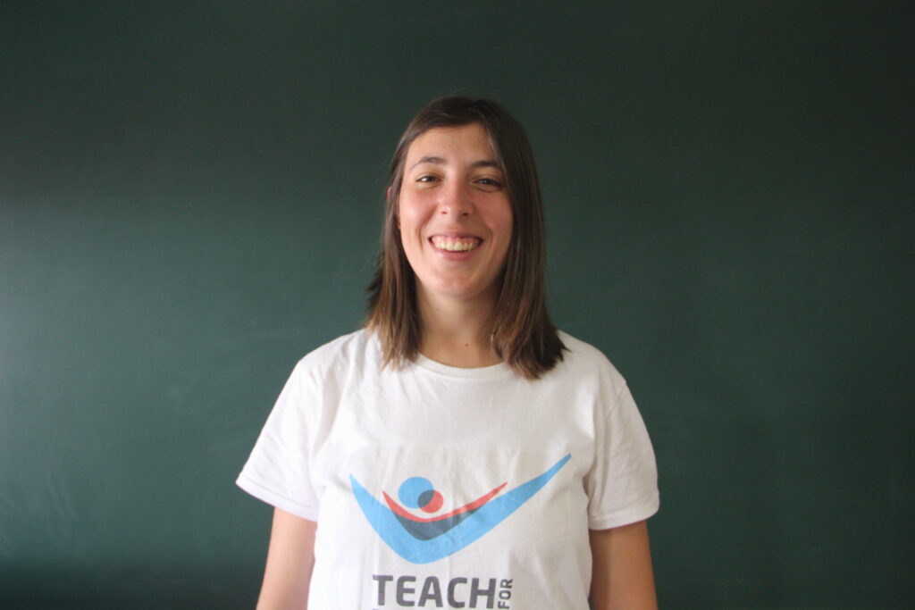 Margarida Simões, Mentora 5ª Geração Teach For Portugal a usar a camisola com o logótipo da Teach For Portugal com um quadro de ardósia como fundo