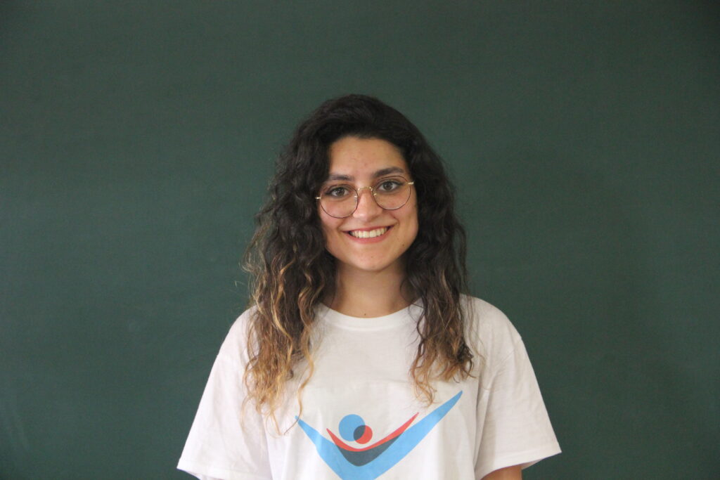 Fernanda Soares, Mentora 5ª Geração Teach For Portugal a usar a camisola com o logótipo da Teach For Portugal com um quadro de ardósia como fundo