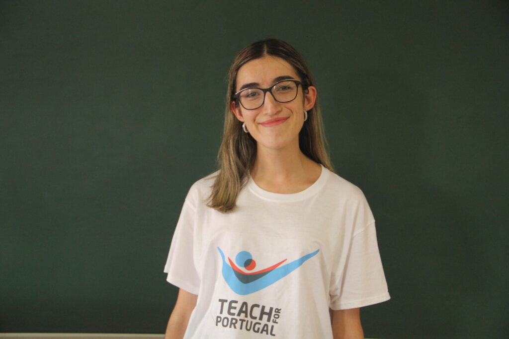 Filipa Neves, Mentora 5ª Geração Teach For Portugal a usar a camisola com o logótipo da Teach For Portugal com um quadro de ardósia como fundo