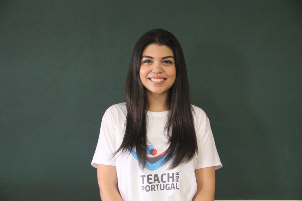 Ana Rita António, Mentora 5ª Geração Teach For Portugal a usar a camisola com o logótipo da Teach For Portugal com um quadro de ardósia como fundo