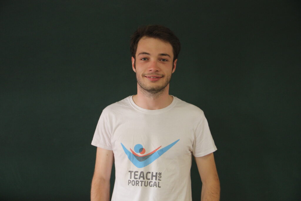 Afonso Sarnadas, Mentor 5ª Geração Teach For Portugal a usar a camisola com o logótipo da Teach For Portugal com um quadro de ardósia como fundo